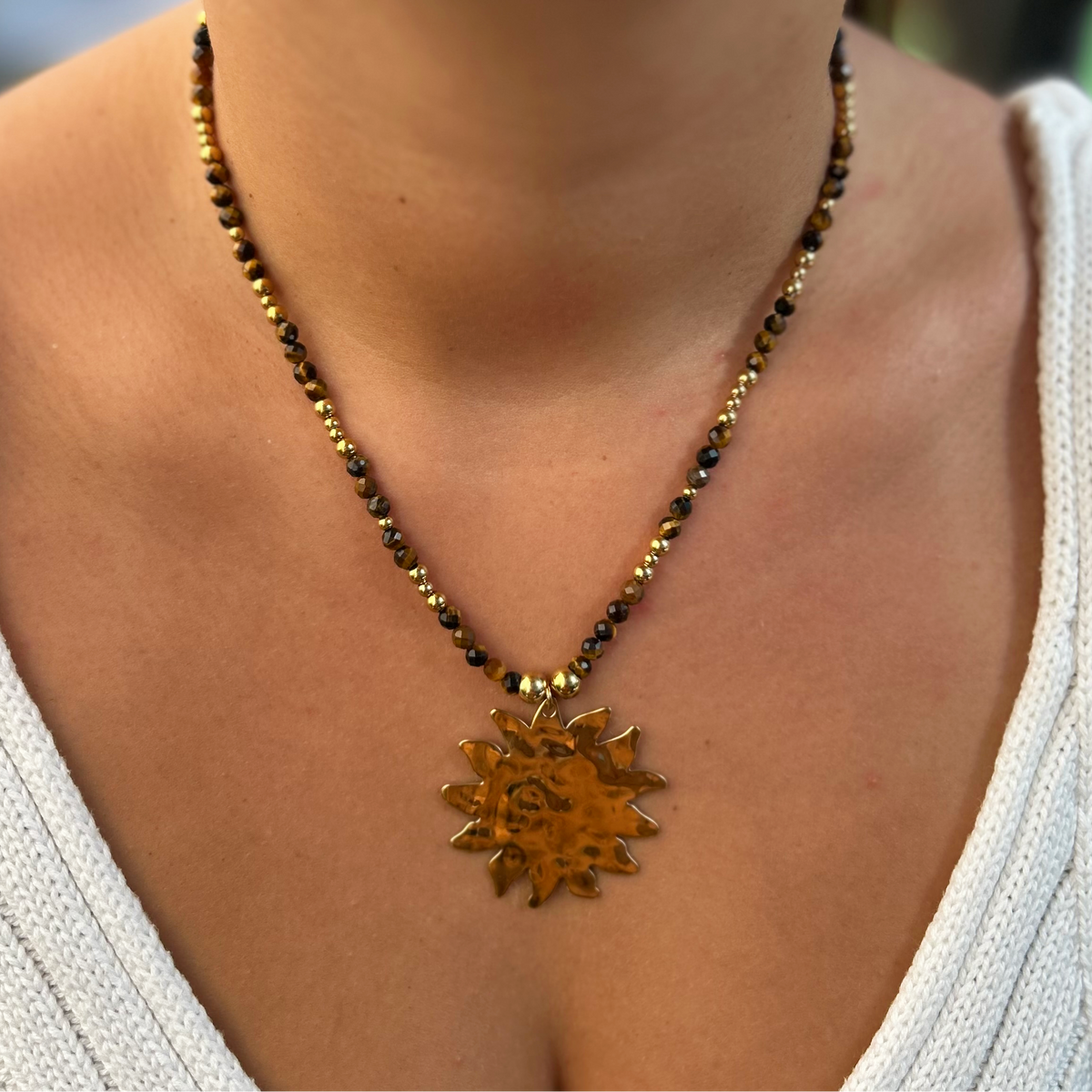 Collier Victoire en œil de tigre, gros plan pendentif soleil porté - L'atelier de Julia