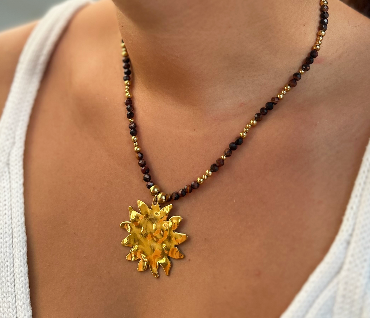 Collier Victoire en œil de taureau, gros plan pendentif soleil porté - L'atelier de Julia