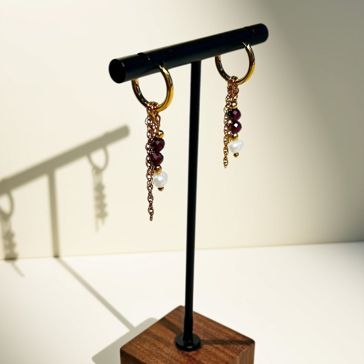 Créoles en grenat rouge et perles d'eau douce, présentées sur présentoir - L'atelier de Julia